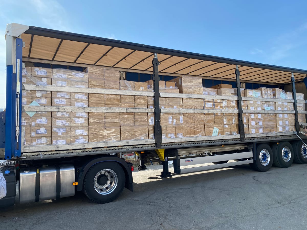 Abtransport aus dem Lager: offener Auflieger, dicht mit Kartonpaletten beladen, bevor der Warenposten den Großhandelshof verlässt